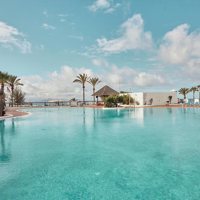 Hotel Sandos Papagayo is een mooi adres voor een heerlijke vakantie op het prachtig eiland Lanzarote. Vele faciliteiten zorgen ervoor dat het u aan niets ontbreekt. U geniet hier ook nog eens van een prachtig uitzicht over zee en bij helder weer kunt u zelfs Fuerteventura zien liggen.Voor de deur van het hotel ligt een klein strandje voor een frisse duik in zee en om af te koelen zijn er ook twee grote zwembaden. Verderop liggen de prachtige stranden Playa Mujeres en Playa del Pozo, waar u uren kunt genieten van zon en zee. Lekker eten kan goed in het restaurant, waar iedere dag weer van alles klaargemaakt wordt en 's avonds kunt u samen proosten bij de bar. Indien u kiest voor een Royal Elite kamer, dan is er een apart restaurant waar u mag eten en de comfortabele Royal Elite lounge, waar drankjes en snacks voor u klaarstaan.